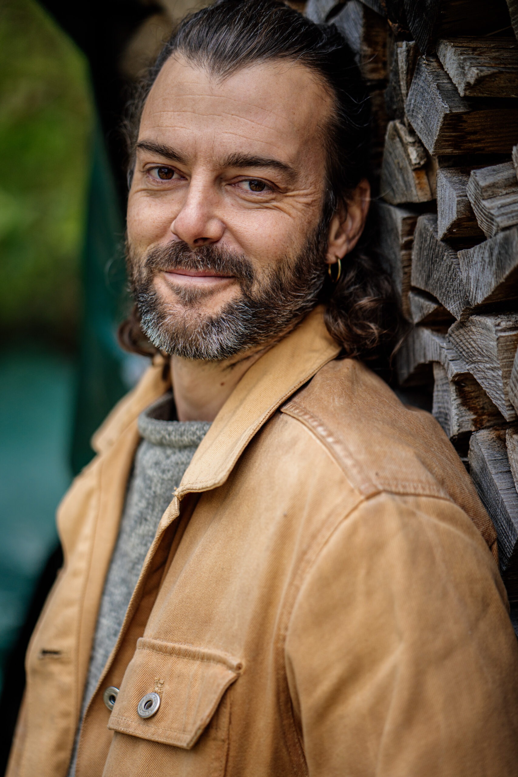 Luca Aeschlimann steht selbstbewusst und lachend vor zwei Olivenbäumen. Im Hintergrund links sieht man eine grosses Gebäude und rechts einige Bäume.